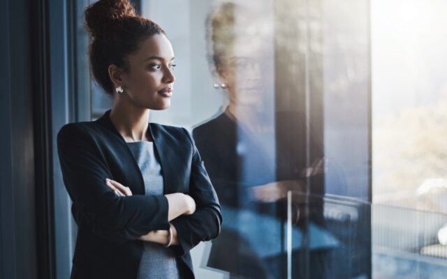 Young business woman looking out window of office.